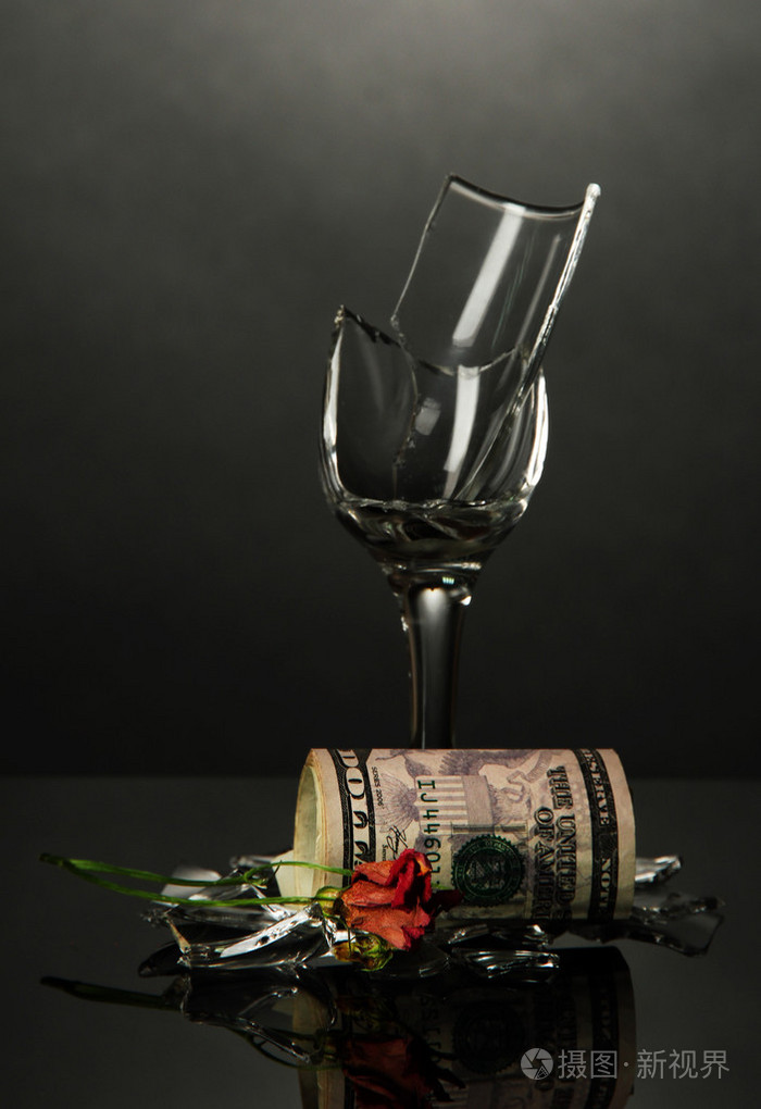 破碎的酒杯和金钱花在灰色背景