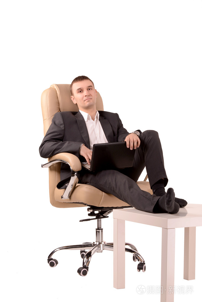 坐在他的脚在桌子上的椅子上的男人