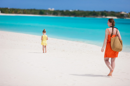 母亲和女儿热带沙滩散步