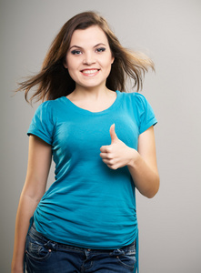 有魅力的年轻女人穿蓝色衬衫。女人出现的拇指
