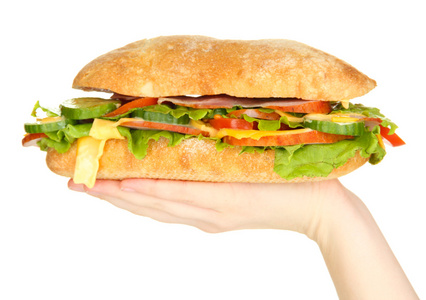 与火腿和蔬菜在手上白色隔离的新鲜和美味三明治