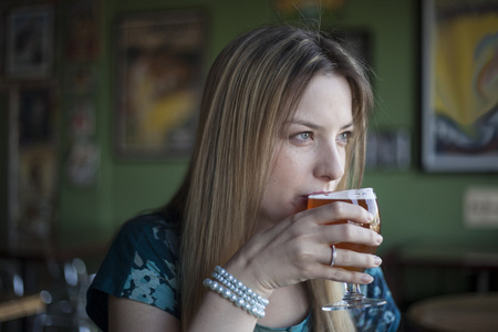 漂亮的蓝眼睛的金发女人喝杯啤酒
