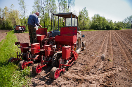 农夫灌装撒种工作土地与拖拉机