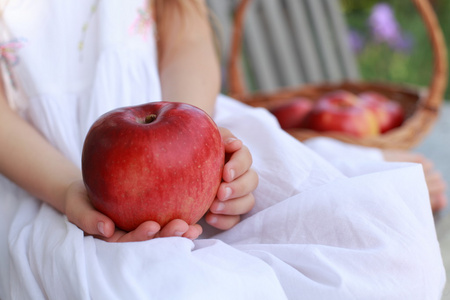 红苹果的长凳上，坐在一个长椅上有红色的有机 applesbasket busket 上的女孩