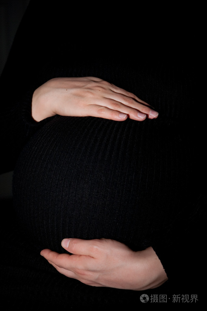 怀孕的女人举行她的肚子里用的手