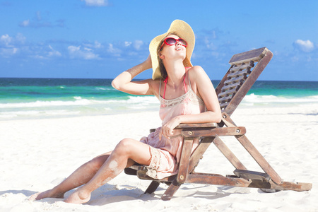 年轻女子在草帽和坐在沙滩椅上的比基尼