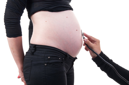 怀孕的女人正由一名医生用听诊器 iso 审查