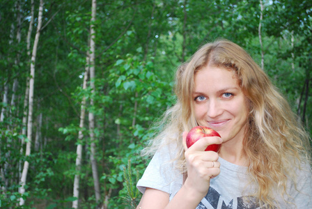 在白桦林中，一个美丽的女孩吃了一个苹果