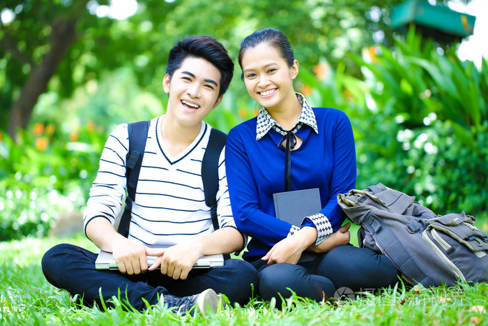 年轻的亚洲学生与计算机和室外的微笑