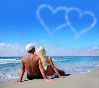 爱的概念夫妇在海海滩看看云的心