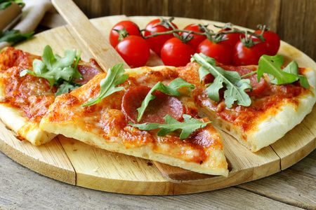 意大利辣香肠比萨饼配番茄汁和香草在木板上