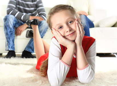 一个女孩躺在地上，微笑着与她的父母在背景上的一幅肖像