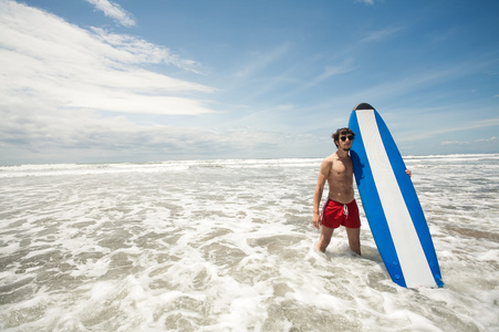强年轻冲浪男子肖像在海滩上的冲浪板。广管局