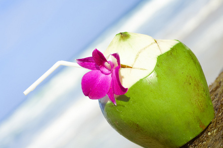 查看好新鲜热带鸡尾酒装饰着兰花在沙滩上
