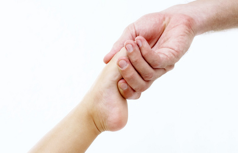 View of mans hand holding babys toe on white background