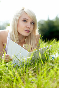 年轻漂亮的女孩读一本书户外