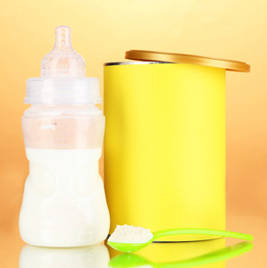 与牛奶和米色背景上的婴儿食品瓶