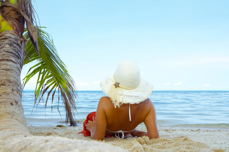 好女人在白色巴拿马和比基尼热带海滩上懒洋洋的视图