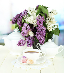 作文与美丽的淡紫色花朵，在明亮的背景上的木桌上的茶水服务