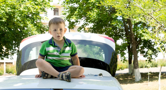 年轻的金发小男孩坐在一辆汽车的天台