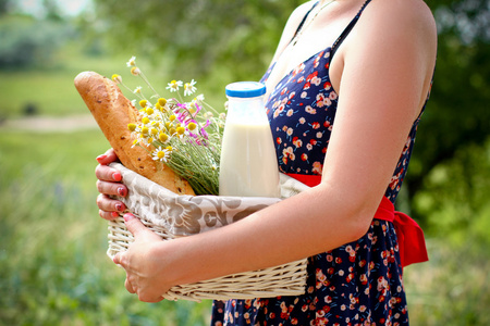 女人在夏天举行篮面包 牛奶和花