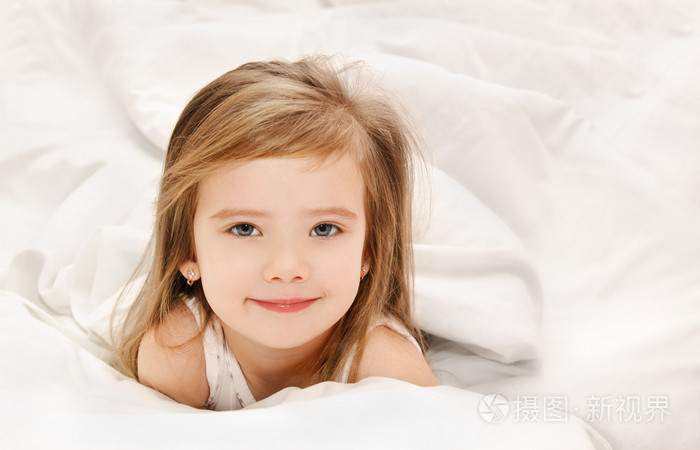 可爱的小女孩在她的床上醒了
