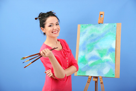美丽的年轻女子画家在彩色背景上的工作，