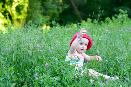 可爱的小女孩坐在绿色的原野