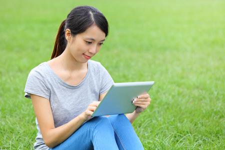 女子坐在草与平板电脑