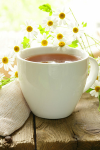 喝杯茶和洋甘菊花朵木制的桌子上