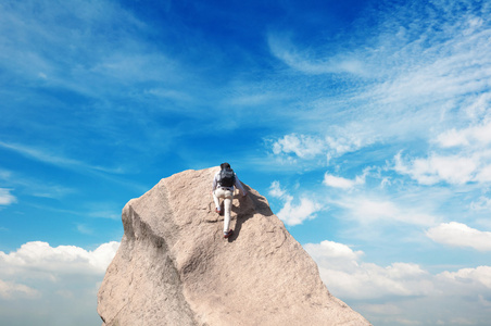 蓝色天空的背景上用石灰石墙上爬的年轻男子