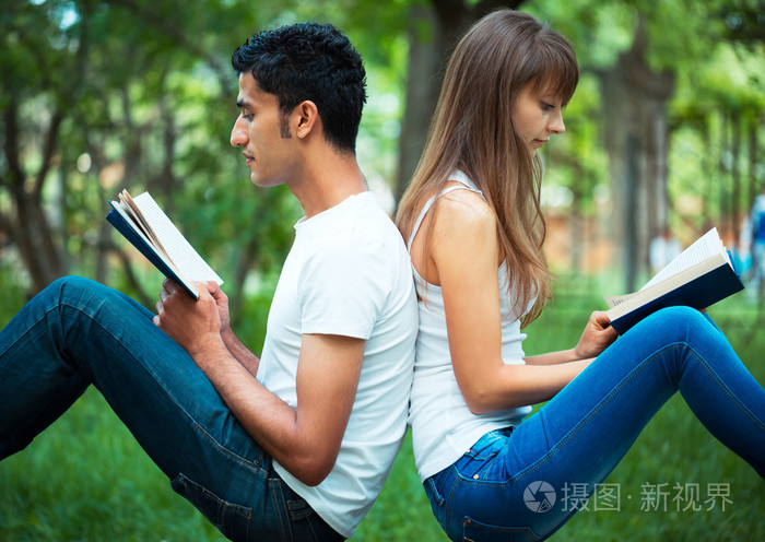 学生背对着背读一本书户外