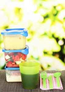 在塑料容器中，在明亮的背景上竹垫上美味的午餐