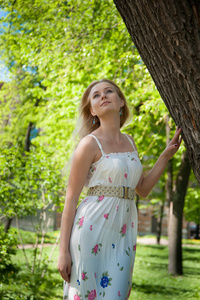 美丽的年轻女人站在树旁