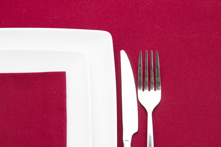 两个白色的正方形的盘上红布带餐具图片