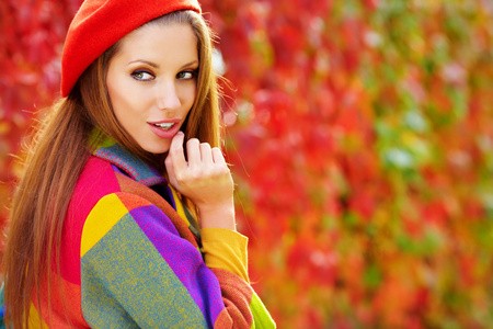 美丽优雅的女人站在一个公园在秋天