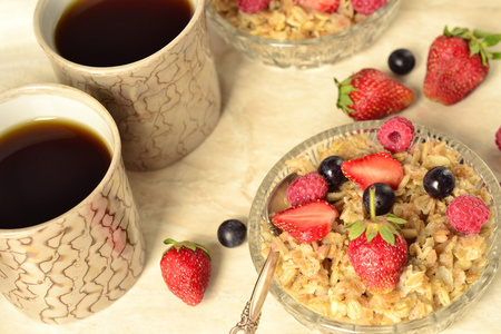 谷物 新鲜浆果在一个玻璃碗和茶的早餐粥