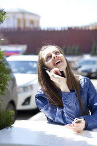 年轻快乐的女人通过电话在大街上调用