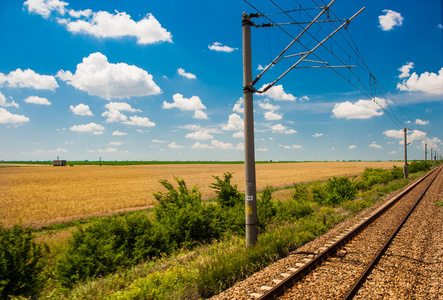 铁路去视界在绿色和黄色的风景，在蓝蓝的天空下与白 clouds.railway 下农村地区多云 sky.scenic 铁路在夏天