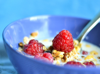 用新鲜水果树莓在蓝色碗麦片