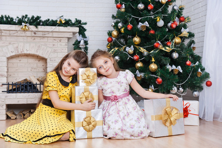两个小女孩附近与礼物的圣诞树