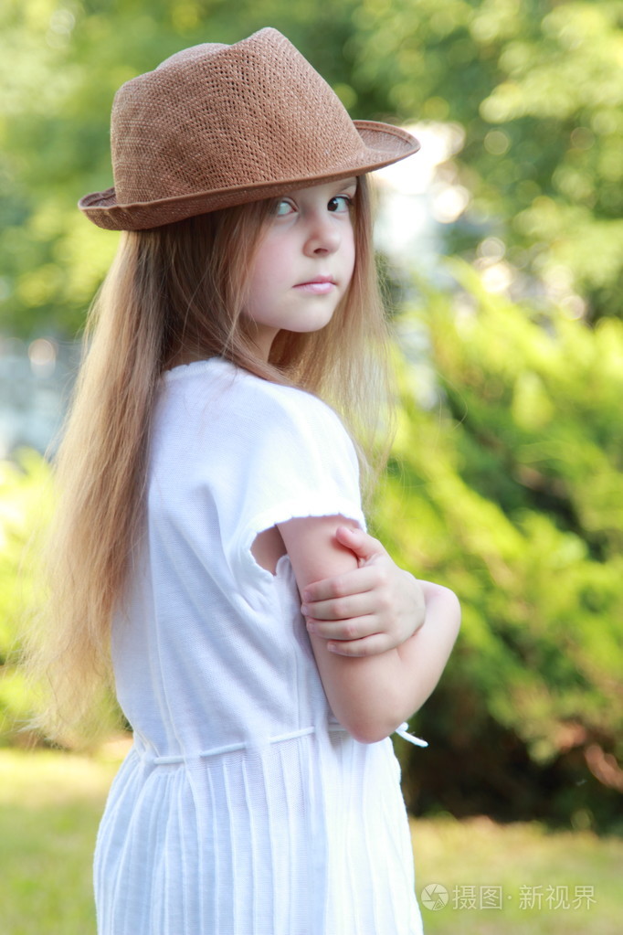 漂亮的小女孩在白色的衣服和帽子户外