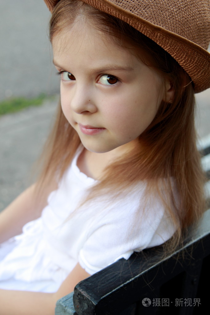 画像中夏公园穿白裙子的小女孩坐在街头长椅上