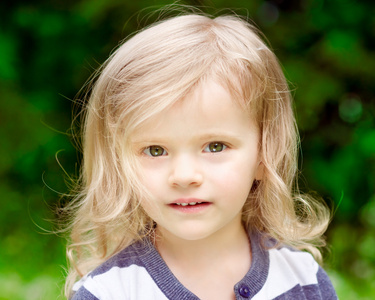 可爱的小女孩的金色卷发在夏季的一天中的特写肖像