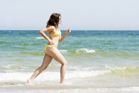 快乐的女人在海滩上运行