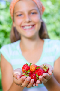年轻的女孩拿在手有机天然健康食品生产草莓。垂直视图