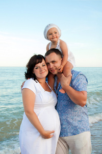 快乐怀孕家庭与海滩上的女儿