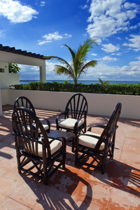 椅子和俯瞰大海的热带露台上的小桌子