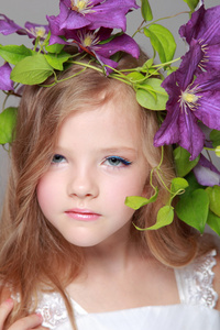 白种人可爱的小女孩漂亮发型与新鲜明亮的铁线莲微笑和照相机的构成