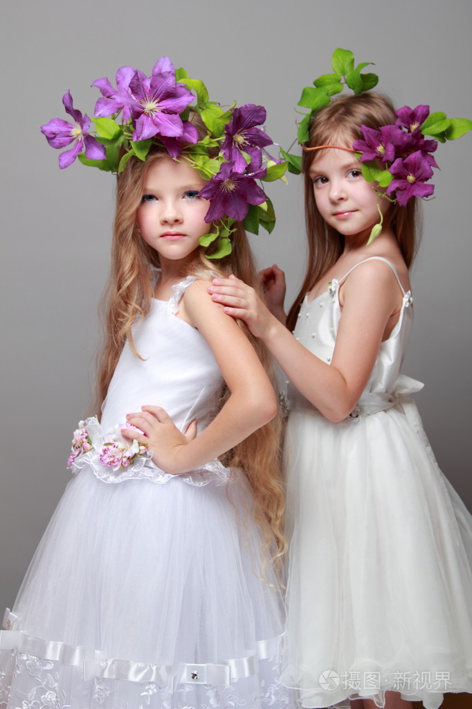 微笑与美丽发型新鲜紫铁线莲的美丽和时尚优雅的礼服的小女孩照片